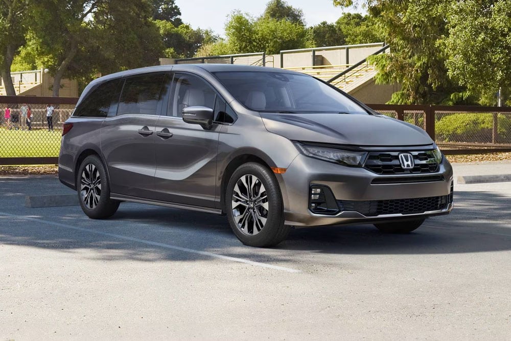 2025 Honda Odyssey minivan in a parking lot, showcasing sleek design and Honda branding, relevant for Honda certified collision repair services and OEM parts.