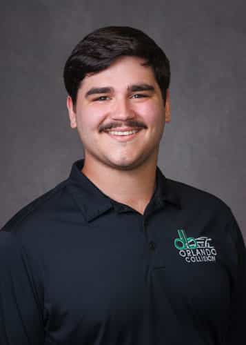 Christian, collision repair technician at db Orlando Collision, smiling in a black polo shirt with the company logo, emphasizing expertise in auto body repairs and commitment to quality service.