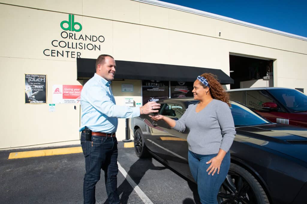 Customer receiving keys from a representative at DB Orlando Collision Center, showcasing service in auto body repair and collision services.