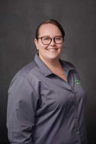 Emma, office administrator at db Orlando Collision, wearing a gray shirt, smiling against a dark background, representing customer service and office support in auto body repair.